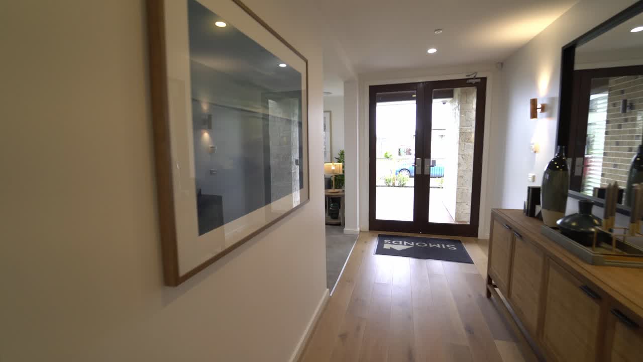 caminando por el pasillo con pisos de madera hacia la sala de estar con alfombra gris y sofá