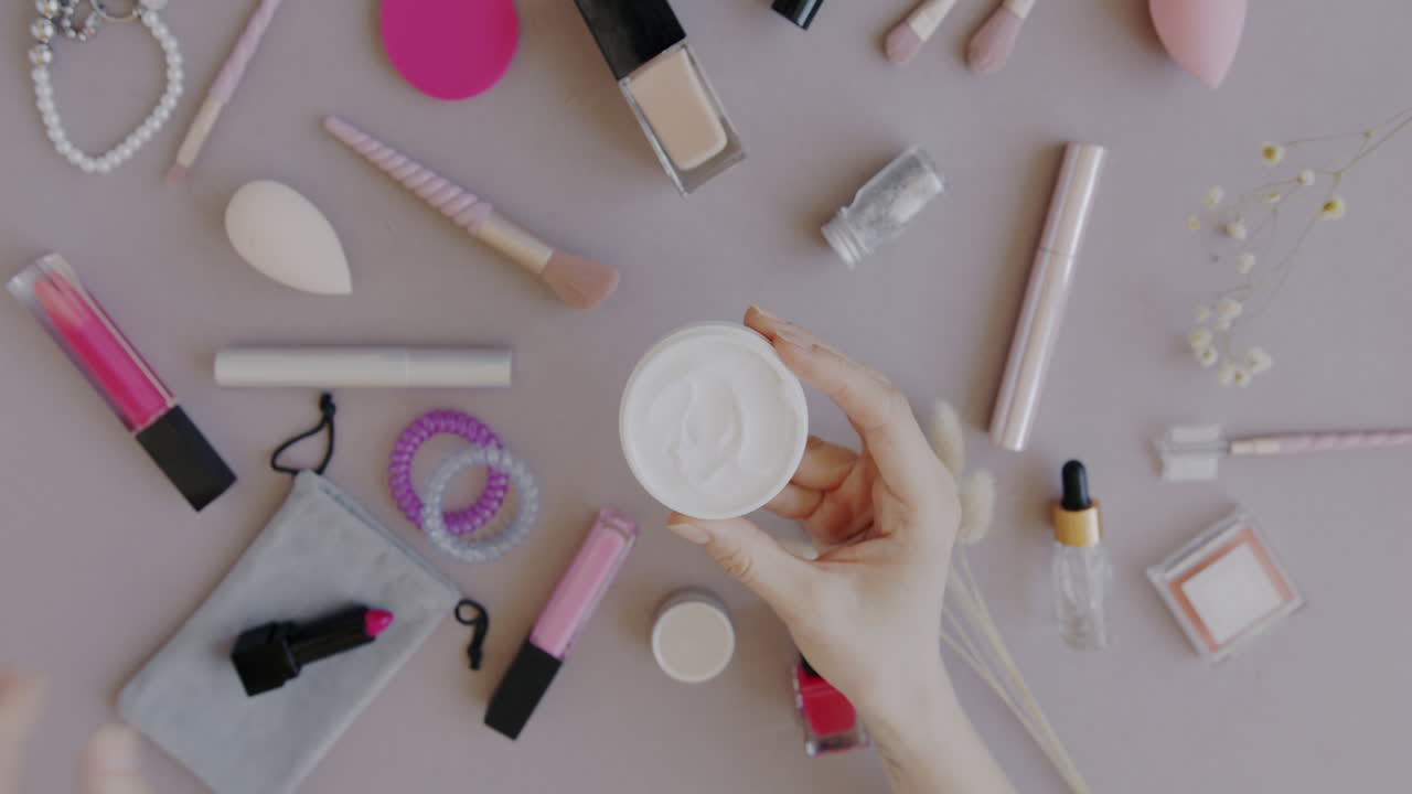 Woman's Hand Holding Cream in a Beauty Flatlay
