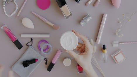woman's hand holding cream in a beauty flatlay