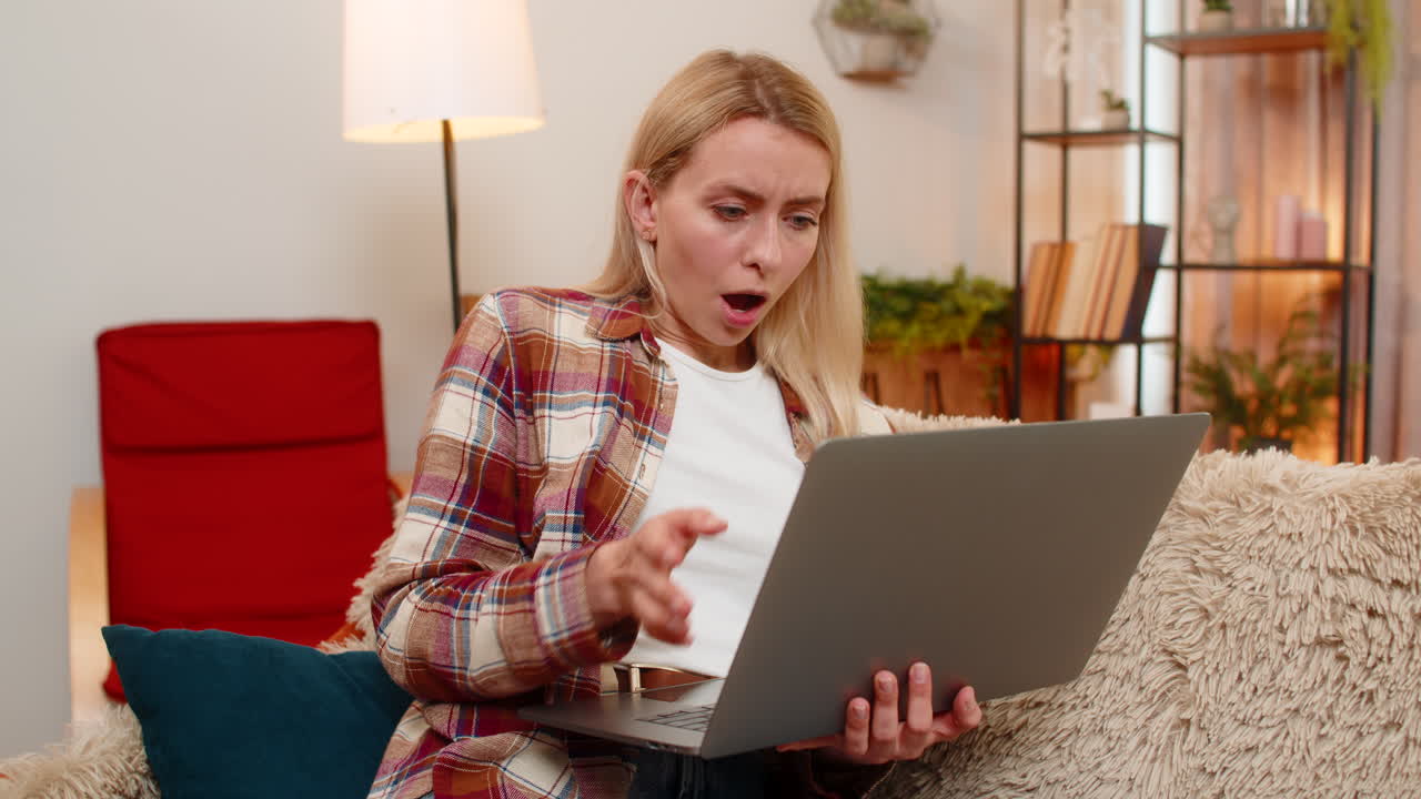 Adult woman shocked by test result on laptop opening eyes wide in surprise and emotional reaction