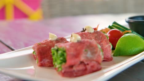 Slow-backwards-dolly-of-fancy-long-appetizer-plate-with-salmon,-salad-and-carpaccio-bites