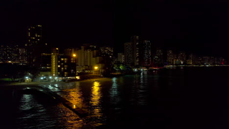 South-to-Southeast-coastline-of-Honolulu-Hawaii-cityscape-reveal-of-aerial-view-from-left-to-right-at-night