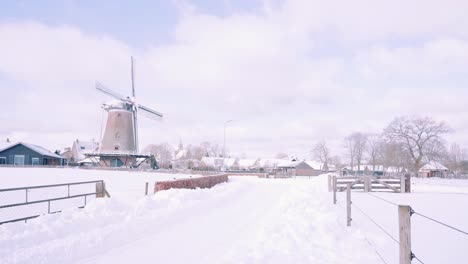 farms and a windmill in a snowy winter in ermelo, netherlands, wide shot