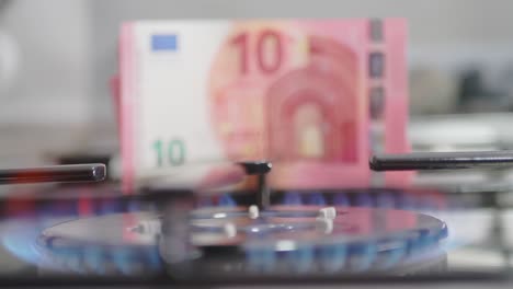 gas burner on and in the background 10 euro banknotes being pulled out. the concept of a steep rise in gas prices