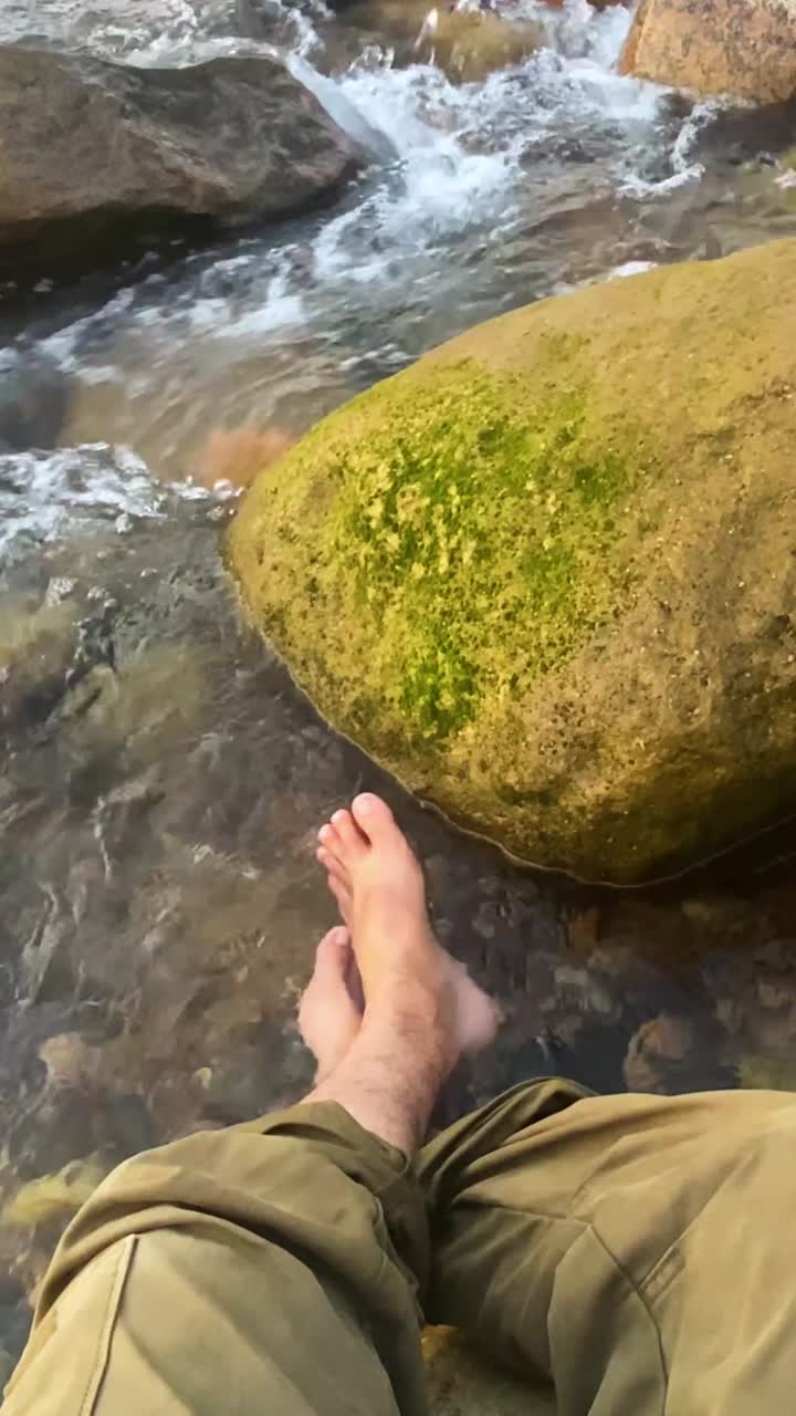 POV of a barefoot traveler relaxing in a clear mountain stream flowing through rocks at sylhet, bangladesh