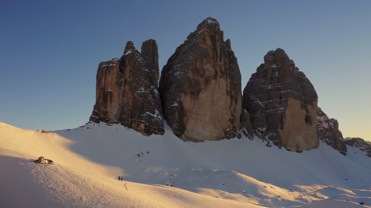 Couple of hikers discover Dolomite and walking on snow at sunset, Tre cime di Lavaredo. Italy