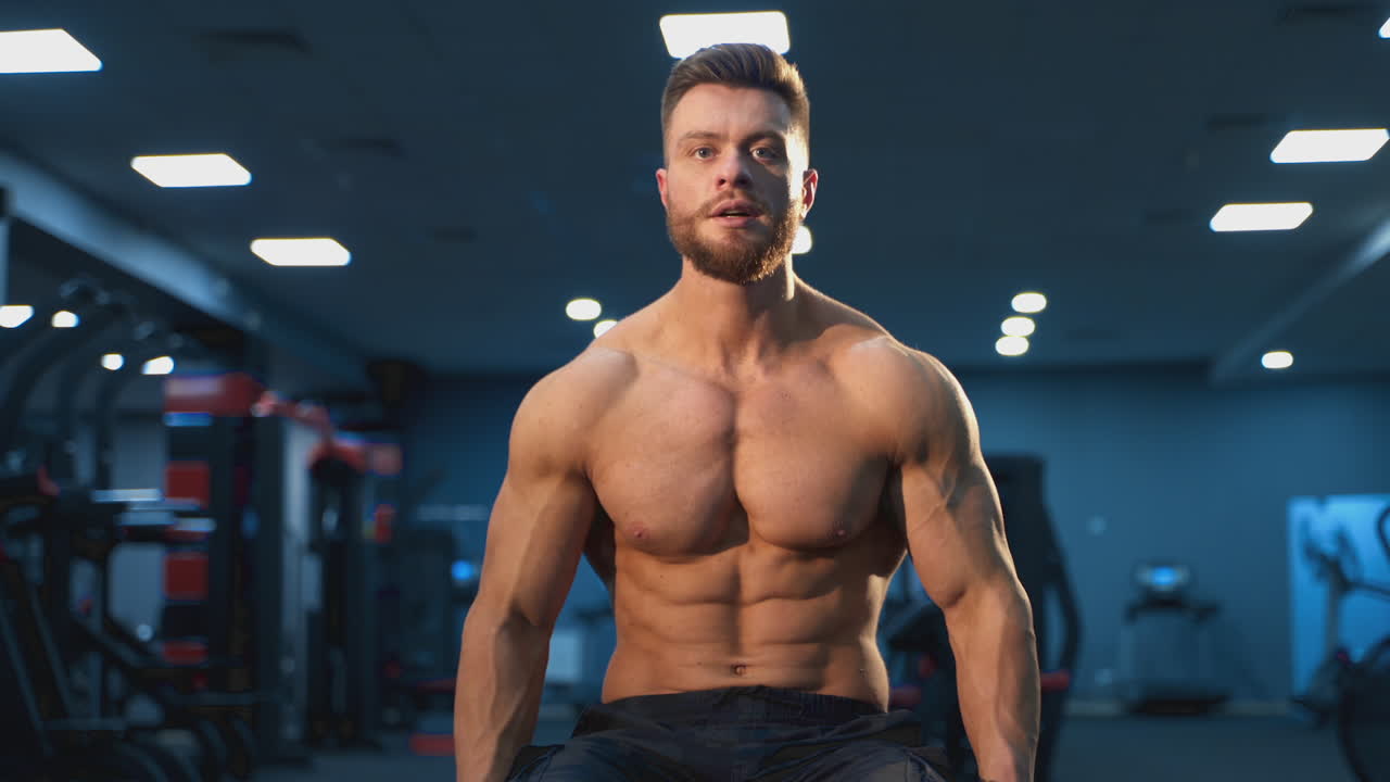 Young shirtless man training hard on the gym. Handsome bodybuilding man have a rest after training.