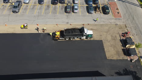 work crew applying new asphalt to a car park