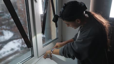 woman installing window weather stripping