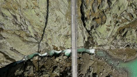 Aerial-top-down-shot-of-high-bridge-between-mountains-and-river-on-ground