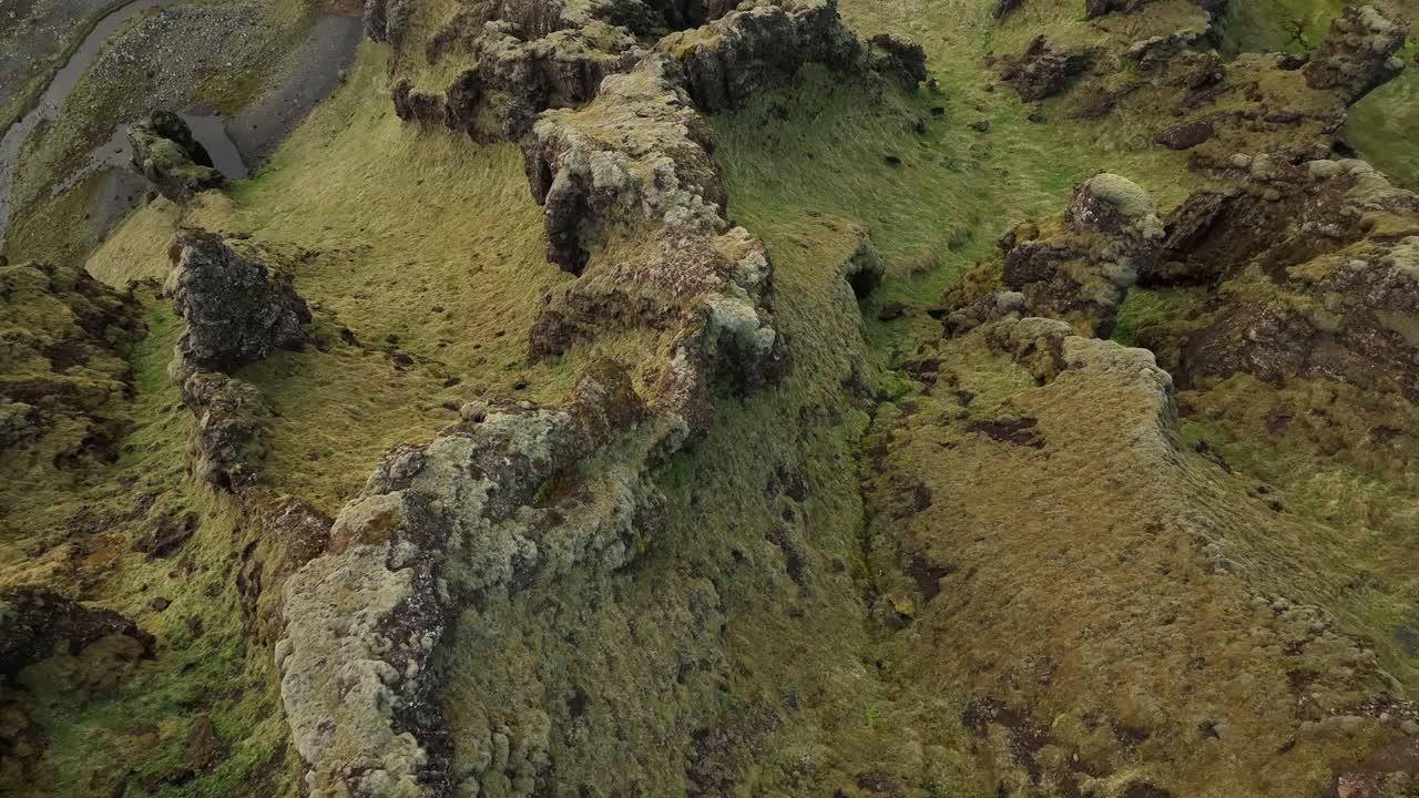 Aerial shot of jagged, moss-covered volcanic ridges in northern Iceland, showcasing the region's unique geology and untouched natural landscape.