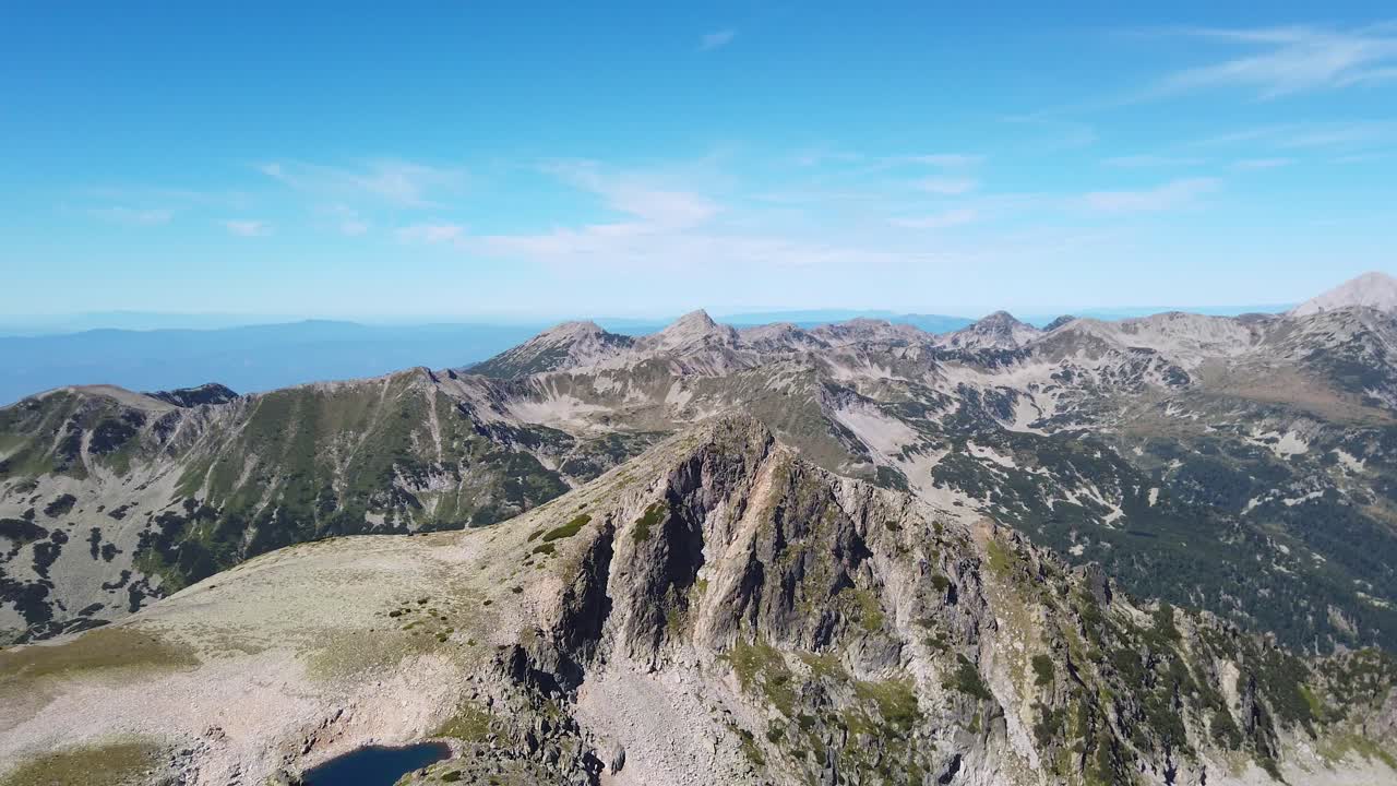 Granite peaks, hills, heights, mountain hills from above. Panoramic view from Strazhite in northern Pirin, Bulgaria. Clear sky. Blue and green panorama.