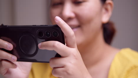 woman having fun playing an online game using a digital mobile phone, smiling as she is gaining more points