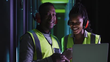 African-american-computer-technicians-using-laptop-working-in-business-server-room