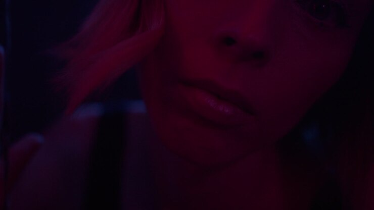 A young woman appears through glittering curtain