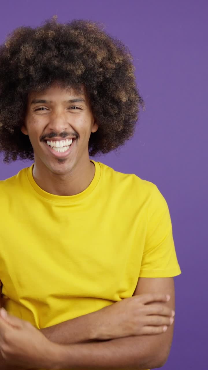 Smiling Man with Afro and Mustache in Yellow T-shirt on Purple Background