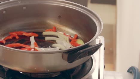 adding bamboo shoots to sauteed onions and paprika to make ginisang labong, an authentic local traditional filipino dish