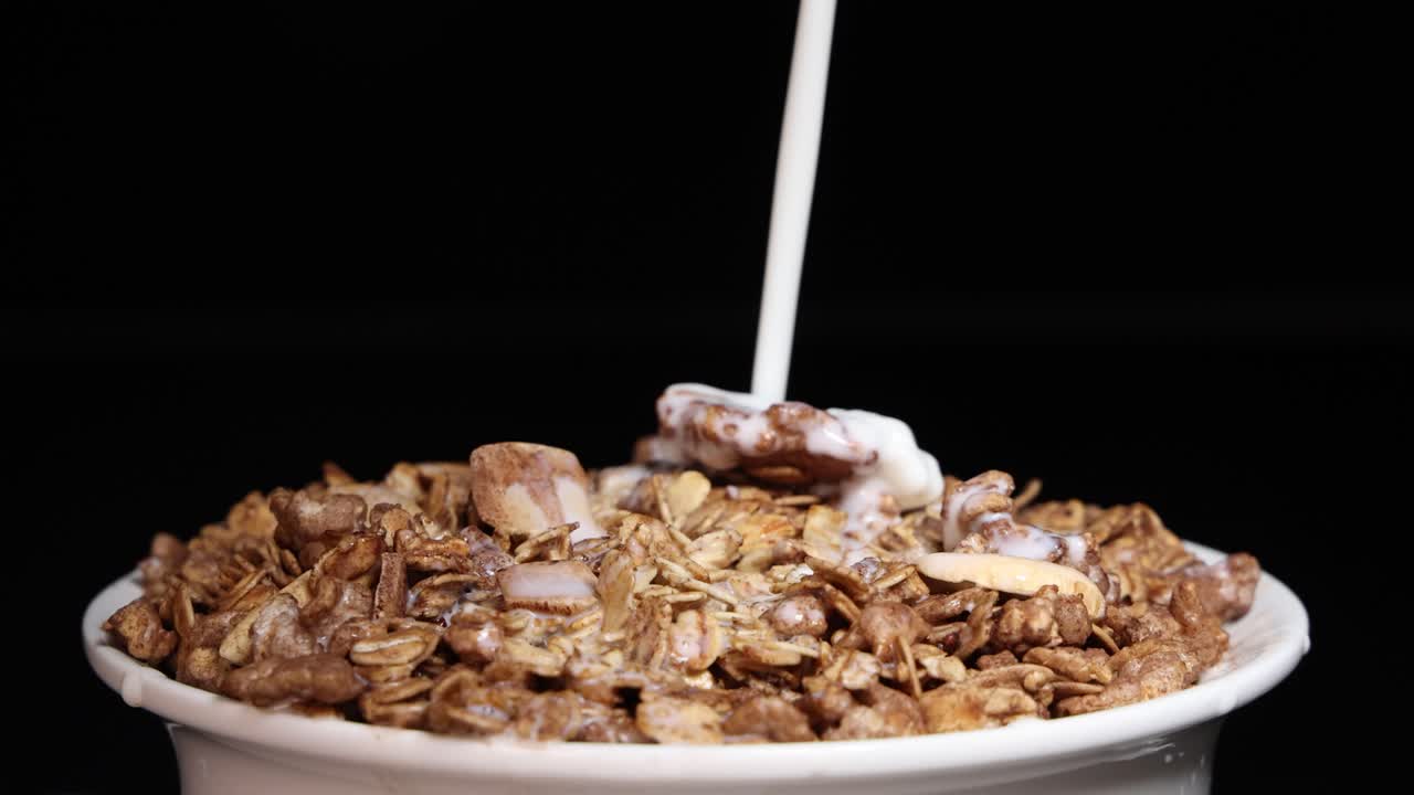Milk cascades over vibrant cereal in a bowl, creating a dynamic and colorful breakfast scene