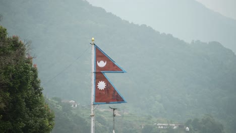 nepalese flag in pokhara in nepal with forests behind at phewa lake in pokhara, country flag of nepal in beautiful scenery