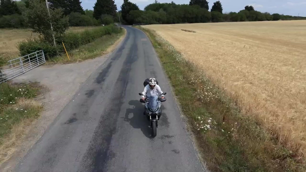 Drone rastreando motocicleta pelo campo inglês no verão