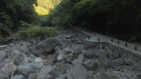 Rocky-River-Bed-with-Forest-of-Yakushima-in-Distance,-Japan