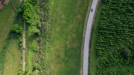 Looking-down-on-a-concrete-and-dirt-road-with-a-car-driving-on-the-narrow-road