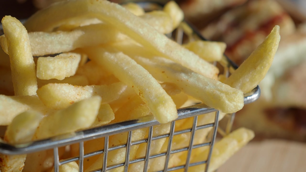 Close-up of golden french fries in a metal basket