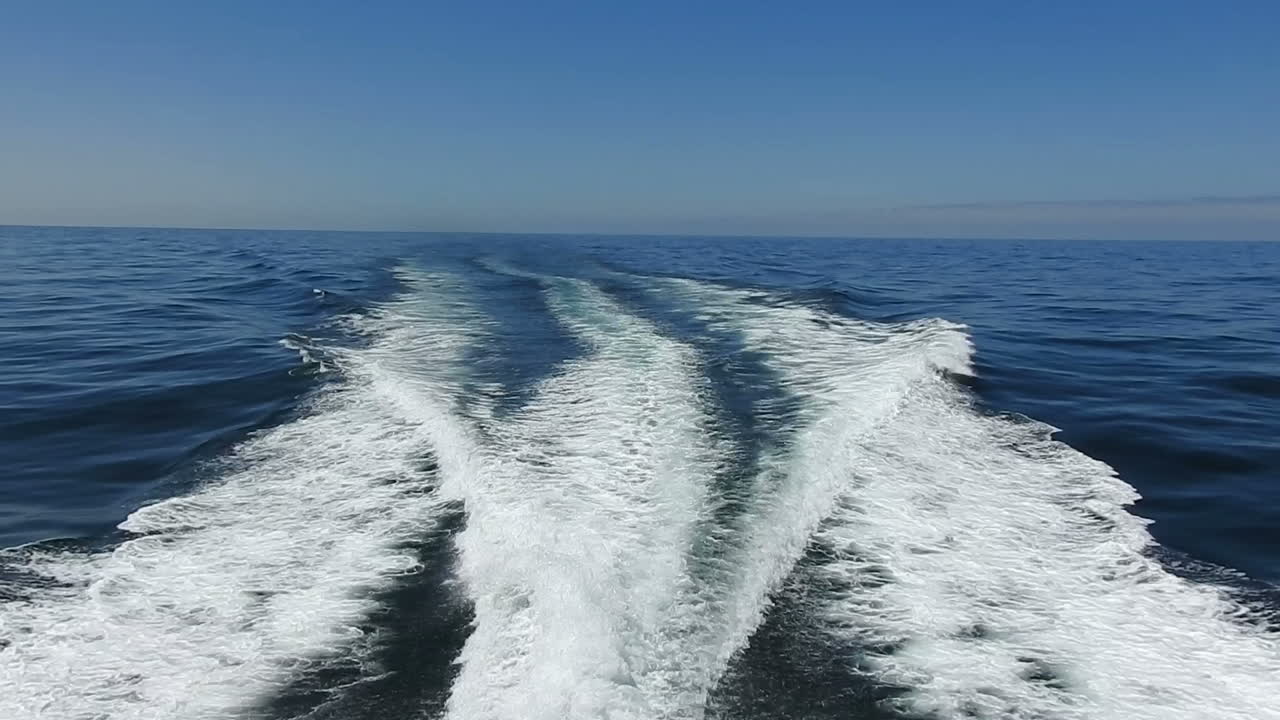 wake of water seen from behind of fast moving motor boat in a clear sky day,Blue sea , water surface.