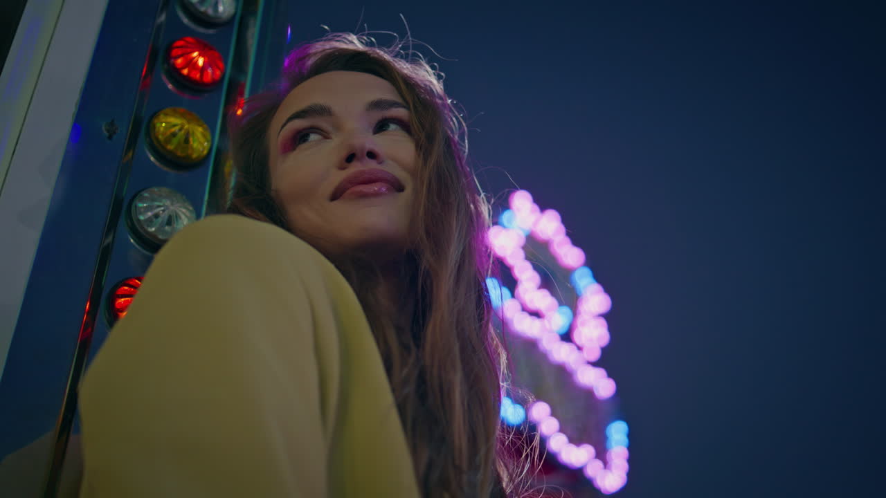 클로즈업 화려한 소녀가 박이는 네온 조명을 포즈로 하고 있습니다. 카루셀에서 미소 짓는 모델