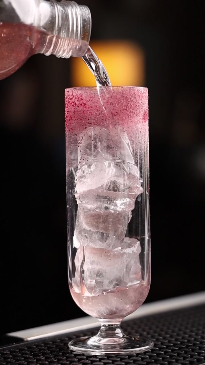 Versando una bevanda frizzante in un bicchiere con ghiaccio e bordo zuccherato