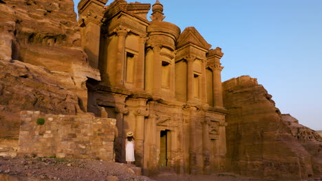 Mujer-De-Pie-Y-Mirando-La-Antigua-Fachada-Del-Monasterio-Ad-Deir-En-Petra,-Jordania-Al-Atardecer