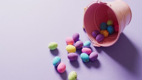 cubo con huevos de pascua coloridos sobre fondo púrpura con espacio para copiar