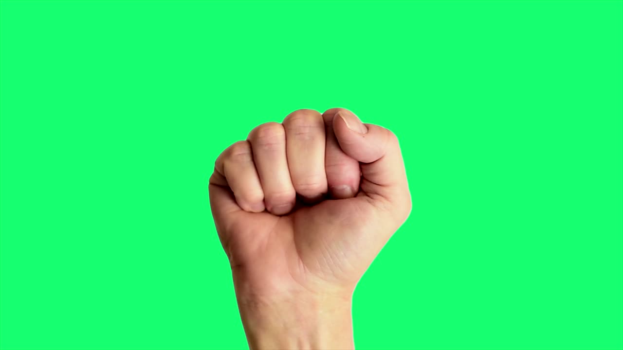 Primer plano de una mano masculina haciendo el clásico signo de poder o puño, sobre un fondo de pantalla verde ideal para croma key