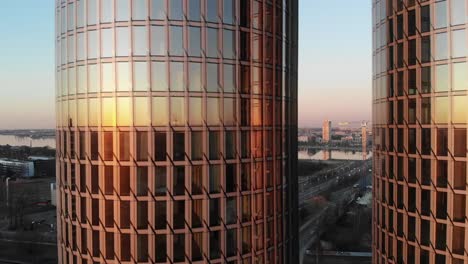 Sunburst-reflection-in-twin-glass-office-buildings-with-cityscape-in-background-in-Riga,-Latvia