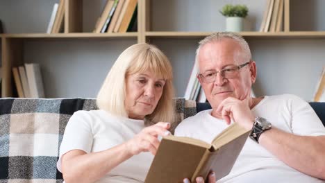 elderly couple reading a book together at home