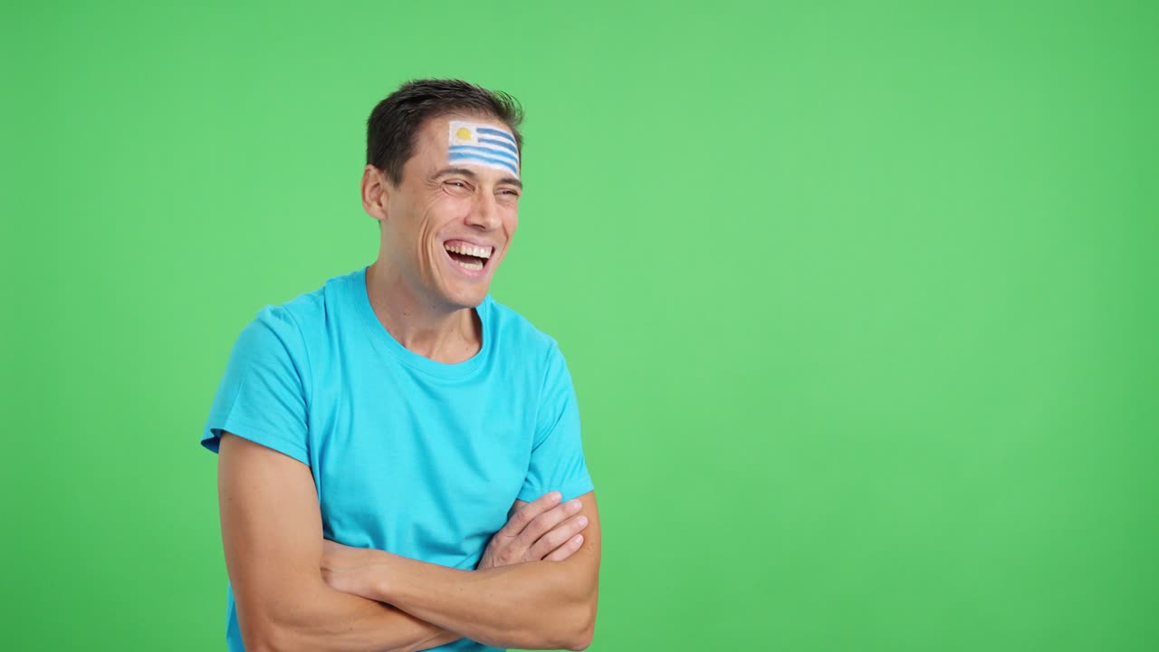 Happy man with uruguayan flag painted on face looking away