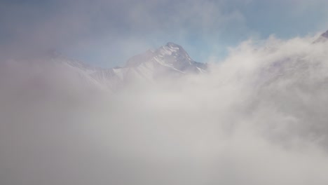 drone video flying through the clouds towards a snowy mountain range