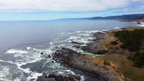 static drone shot of ocean waves crashing against oceanside rock formations - 4k 30fps aerial drone footage of the oregon coast