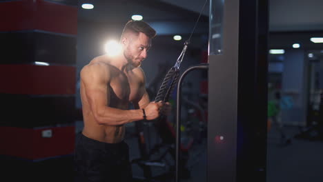 sportsman with naked torso doing workout. athletic man with muscular body exercising near the simulator in the modern gym. strength training at fitness club.