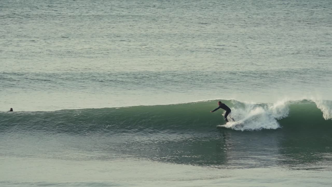 Surfer catching wave, following view