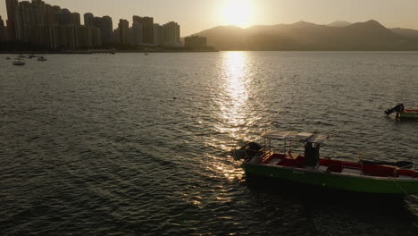 Backward-drone-shot-of-a-beautiful-river-and-boats-in-Hong-Kong-at-sunset