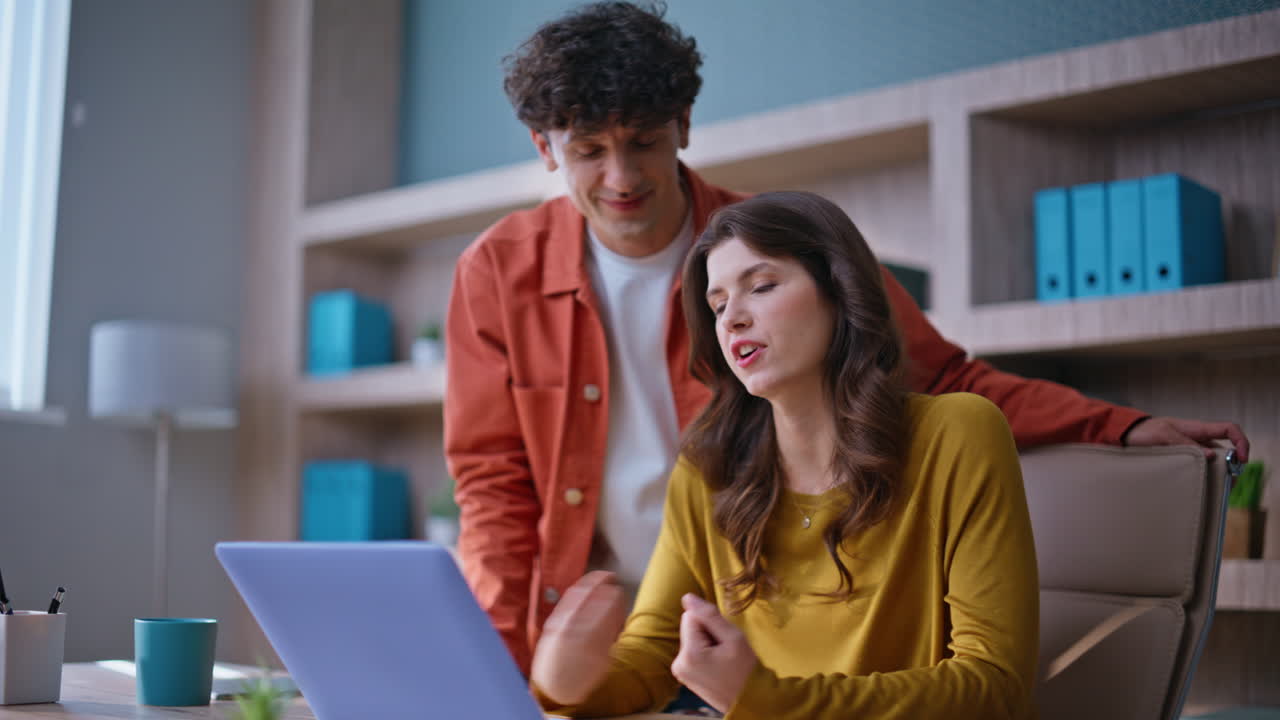 Smiling colleagues video calling by laptop in modern office space closeup