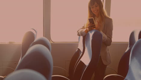 caucasian businesswoman smiling while using smartphone standing in the bus