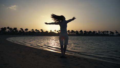 young woman dancing at sand beach. beautiful girl having fun near sunset sea.