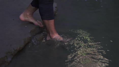 primer plano de las piernas de un hombre caminando por el agua fría, capturando el movimiento y las salpicaduras