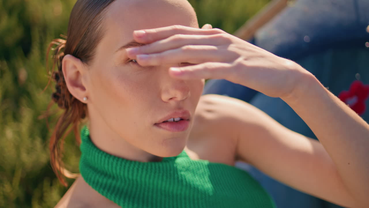 초원 여성은 일몰 클로즈업에서 카메라를 찾고 있습니다. 매력적인 패션 모델이 휴식을 취하고 있습니다.