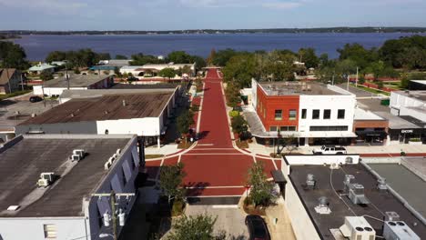 drone dolly above red brick road and white sidewalk push in to open blue lake in distance