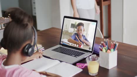 African-american-girl-using-laptop-for-video-call-with-african-american-school-friend-on-screen