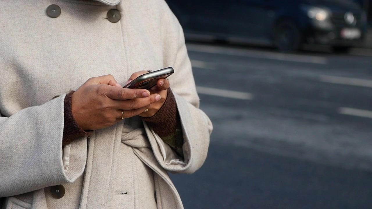 Persona che utilizza uno smartphone in una strada cittadina