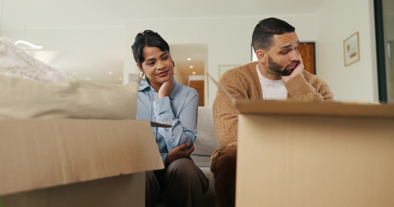 Tired Couple Sitting on Sofa Surrounded by Moving Boxes